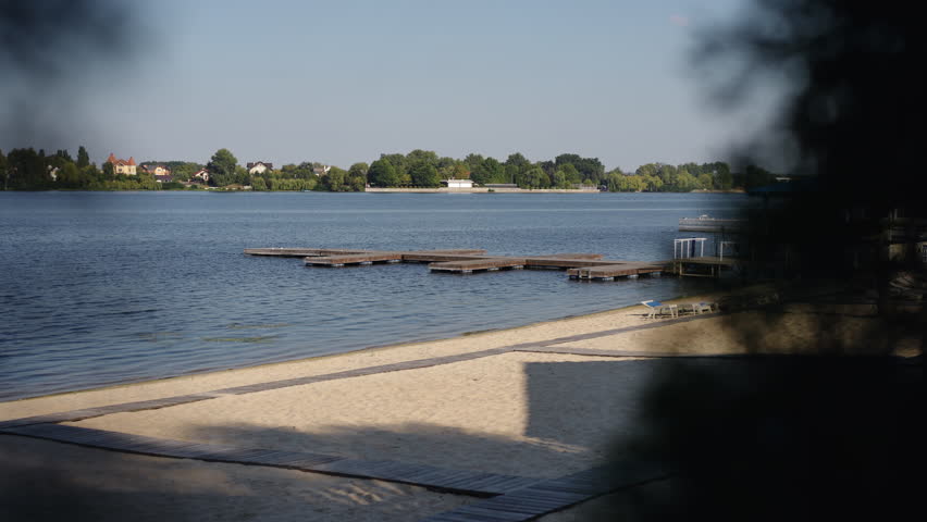 A serene and peaceful lakeside scene showcasing beautiful docks, calm waters, and a lovely sandy beach