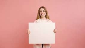 Young woman holding blank white sign on pink background - Powered by Shutterstock - Get 15% off with code: PIKWIZARD15