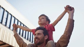 Closeup cheerful father son piggyback riding in street. Handsome man and kid spending time together on alley. Adorable boy spreading arms. Child and daddy having fun walking. Happy childhood concept - Powered by Shutterstock - Get 15% off with code: PIKWIZARD15