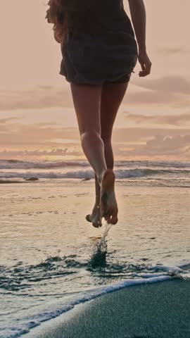 Beautiful Woman Running on Marine Beach and Wet Legs Shape Moving in Water. One Adult Girl at Bright Scenic Sea Going Swim or Splash. Modern Romance of Ocean Bathing and Amazing Summer Sky at Sundown