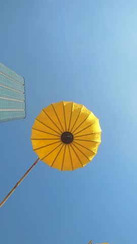 Traditional fabric lanterns against the blue sky. Bright yellow lanterns swing in the wind on a sunny day
