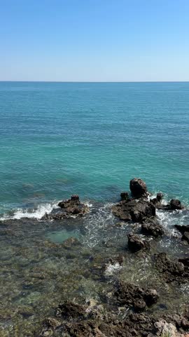 A serene horizon contrasts with the restless sea as foamy waves swirl around jagged rocks—a visual dance between calm and kinetic energy. Digital detox, wellness, mindfulness, zen, relaxation