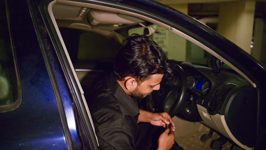 Frustrated Man Starts Car Quickly in Basement Garage, Muslim Guy Shows Annoyance While Gripping Steering, Agitated Male Puts Key into Ignition at Parking Lot, Tense Driver Prepares for Exit, Annoyed