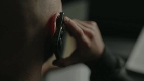 Close-up view from shoulder of unrecognizable businessman holding phone to ear during serious conversation, conducting business negotiations sitting at desk with laptop and paper document, slow motion - Powered by Shutterstock - Get 15% off with code: PIKWIZARD15