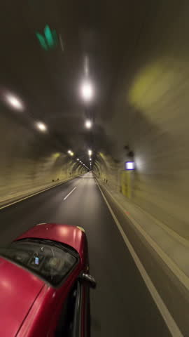 Vertical video. Red Car Moving on a Mountain Road With Motion Blur Showing High Speed and Scenic Nature Around