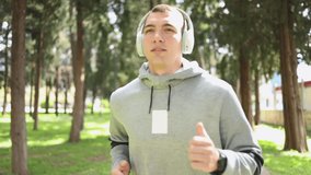 Young man running in the park listening to music with wireless headphones - Powered by Shutterstock - Get 15% off with code: PIKWIZARD15