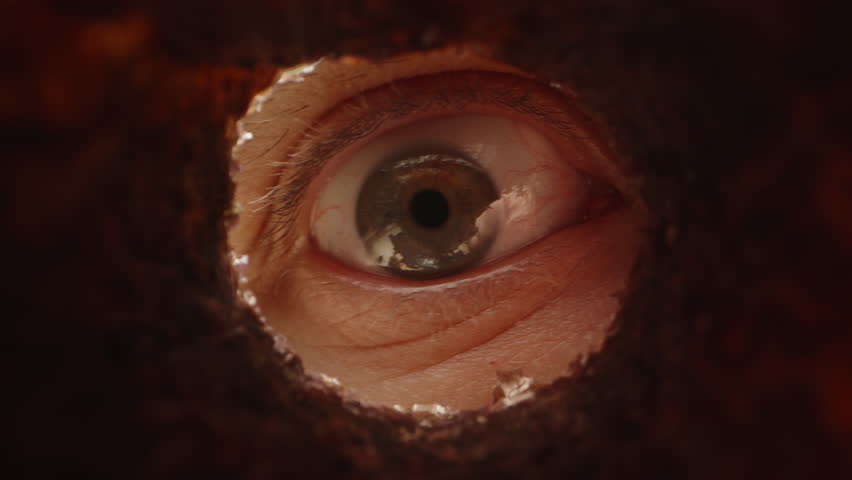 A Male Eye Suddenly Appears Through an Irregular Hole, Creating a Suspenseful Peeking Concept with Dramatic Lighting in a Macro Close-Up Shot
