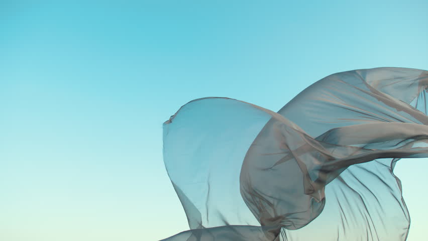 Delicate, translucent fabric gracefully billows in the wind against a vast sky. Soft waves and fluid motion create an ethereal, dreamy atmosphere. Light and shadow play through the sheer, flowing text