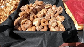 A display of assorted pastries including sugar-coated donuts, croissants, and a raspberry tart, arranged on a black cloth at a market or bakery. - Powered by Shutterstock - Get 15% off with code: PIKWIZARD15