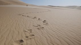 Man walking alone in a sand dunes. Footprints in a desert. Sahara desert near Siwa oasis in Egypt. Handheld real-time footage - Powered by Shutterstock - Get 15% off with code: PIKWIZARD15