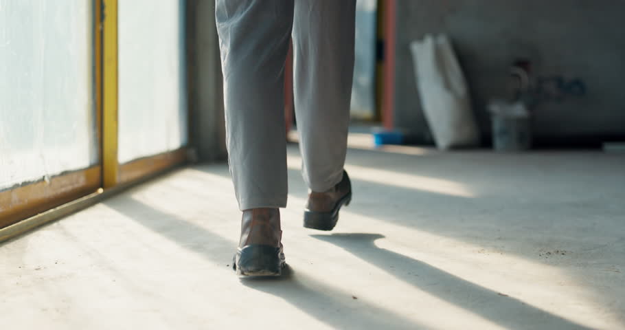 Construction, worker and legs of person walking for project, development and evaluation of progress. Contractor, boots and feet on floor in building for civil engineering, inspection and renovation