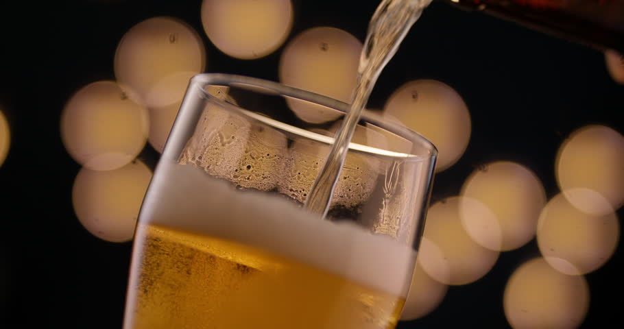 Craft beer pouring into clear glass foam rising bubbles sparkling cinematic view perfect for advertising social gathering product promotion or modern masculine evening lifestyle video content