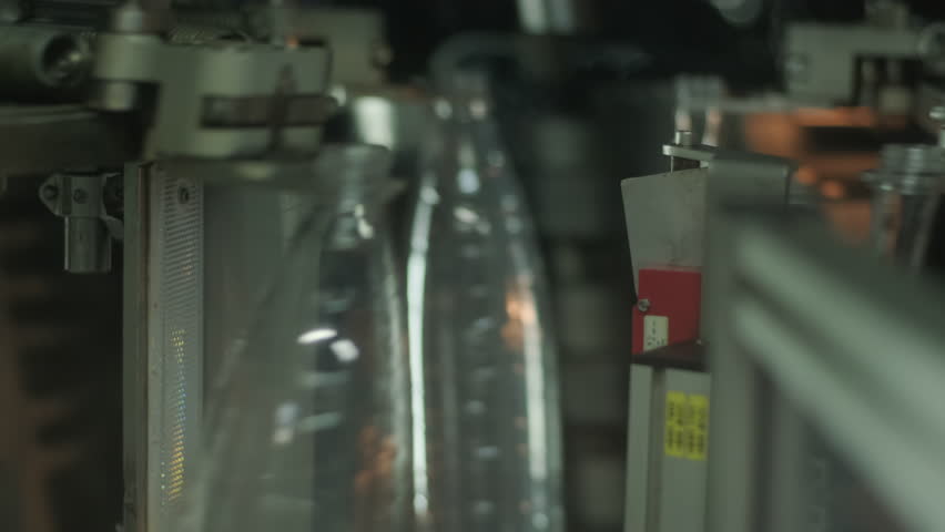 Automated production line for bottling water or juice in a modern beverage factory. Plastic bottles move on conveyor belts through filling, capping, and packaging stages in industrial setting.