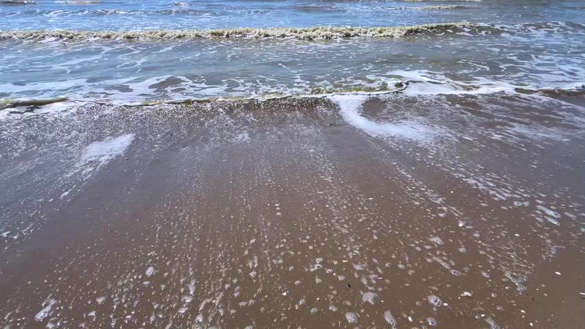 Close-up view of energetic sea waves crashing rhythmically on the beach. Perfect for content related to energy, coastal scenery, or nature backgrounds.