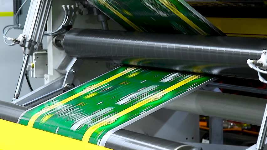 Technology of automatic label printing machine with the digital control panel is printing on continuous plastic film for wrapping on food product packaging in the printing factory.