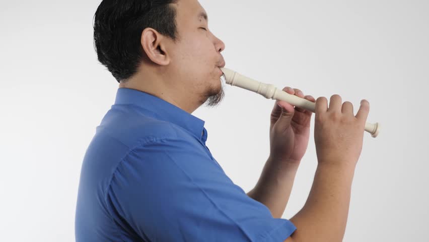 Young adult Asian man playing recorder flute, musical instrument