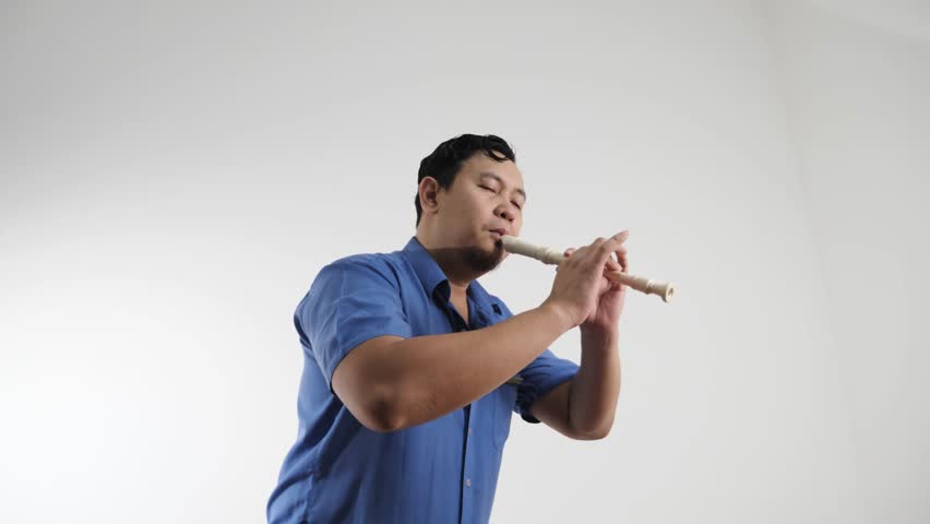 Young adult Asian man playing recorder flute, musical instrument