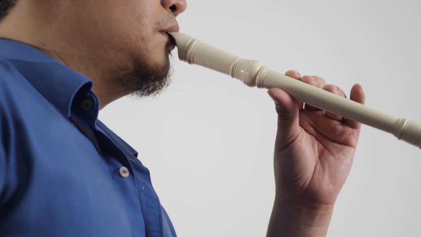 Young adult Asian man playing recorder flute, musical instrument