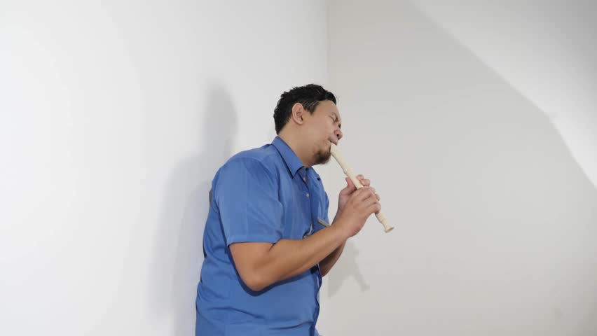 Young adult Asian man playing recorder flute, musical instrument