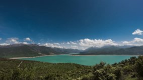 Mountains and lake video timelapse for background. View of lake or reservoir Charvak in mountains. Cumulus clouds swirl over mountains. Blue sky over turquoise water surface. Joyful peaceful cinematic - Powered by Shutterstock - Get 15% off with code: PIKWIZARD15