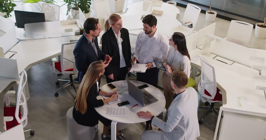 Business people team engaged in negotiation and conversation around a round table during a work meeting in the office. The collaborative discussion highlights teamwork and professional focus.
