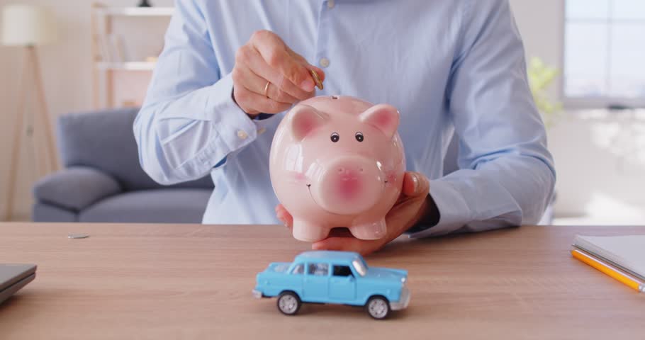 Putting coin in piggybank happy saving money, toy car at office table, planning counting to save money, motivated for result, visualize plan of buying new automobile, dream visualization, financing