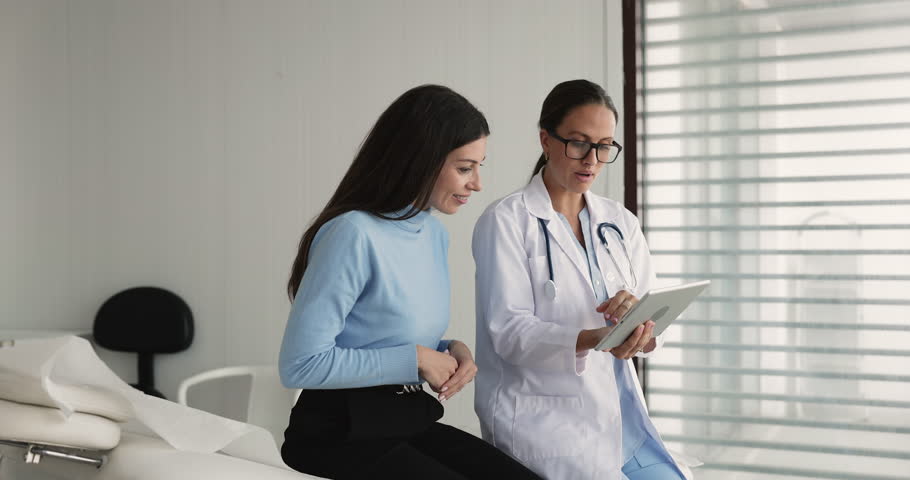 Doctor showing lab tests results or MRI scans on tablet to woman patient, provide diagnosis explanation, health condition based on analysis, explaining treatment plan, showing rehabilitation exercises