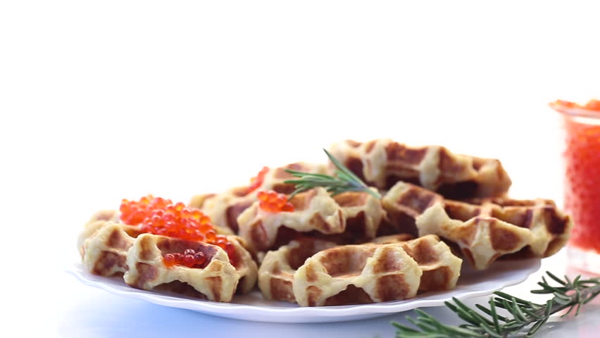 Potato waffles with red caviar on a white background