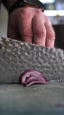 Chef cutting onion on cutting board in restaurant kitchen