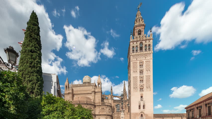 The Seville Cathedral and Giralda Tower timelapse hyperlapse in Seville, Spain. The largest gothic cathedral in the world, UNESCO heritage site, located on Virgen de los Reyes square under a blue sky