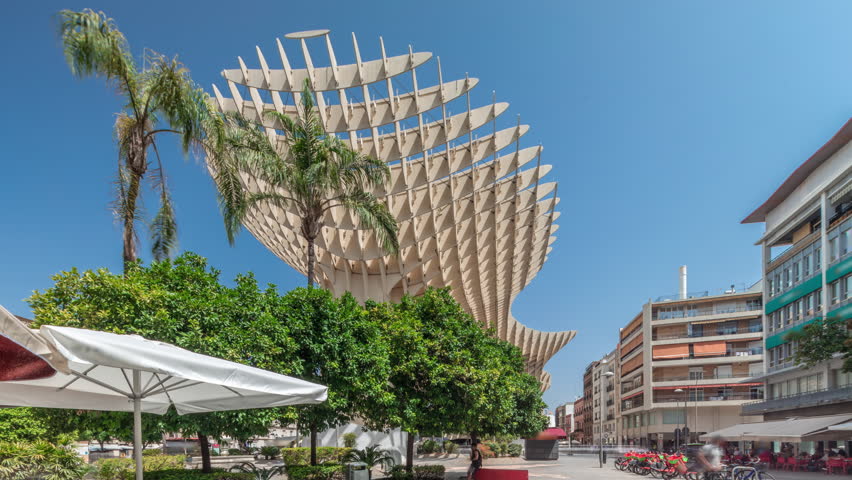 Metropol Parasol in Encarnacion Square timelapse hyperlapse, a futuristic wooden structure with a panoramic walkway and an archaeological museum. Blue sky, trees and cityscape in Seville, Spain.