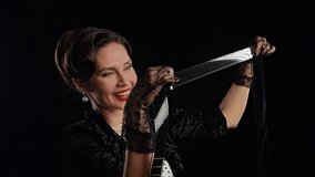 Professional model in studio. Retro woman actress with pin-up hairstyle and makeup isolated on black background, looks through long film reel tape, smiling positive expression. Slow motion. - Powered by Shutterstock - Get 15% off with code: PIKWIZARD15