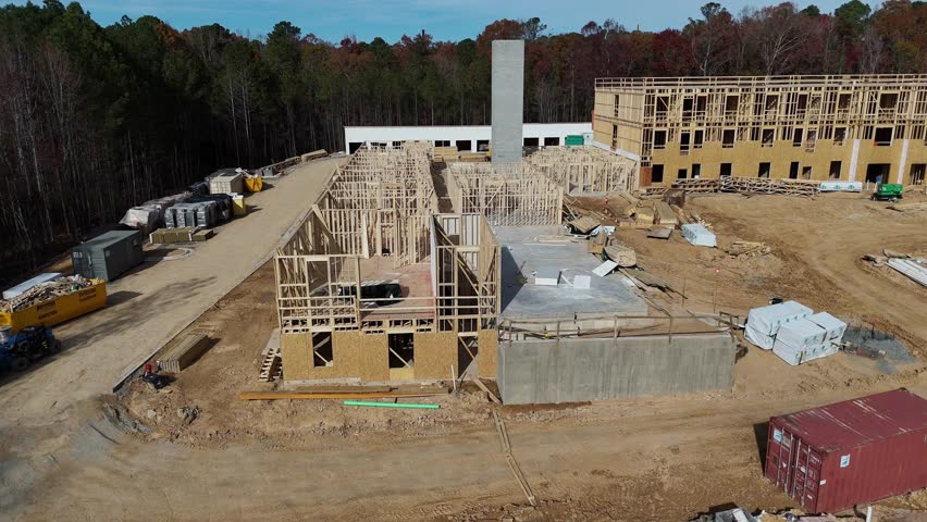 An aerial view of a large construction site displaying various framed buildings along with heavy equipment