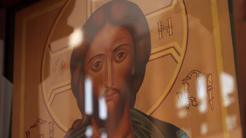Light reflections dancing across ornate jesus christ icon, revealing intricate details within traditional orthodox church interior, symbolizing spiritual depth and sacred imagery