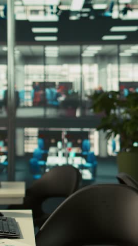 Vertical video Business graphs and performance metrics on monitors in workplace, handheld camera shot. Office desk setup in bright corporate environment with monitors displaying data analytics