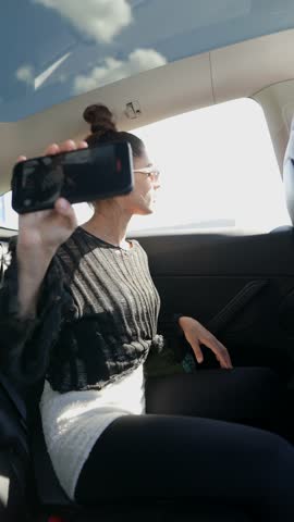 A Stylish Woman is Joyfully Singing While She is Fully Enjoying a Scenic View from Inside a Car