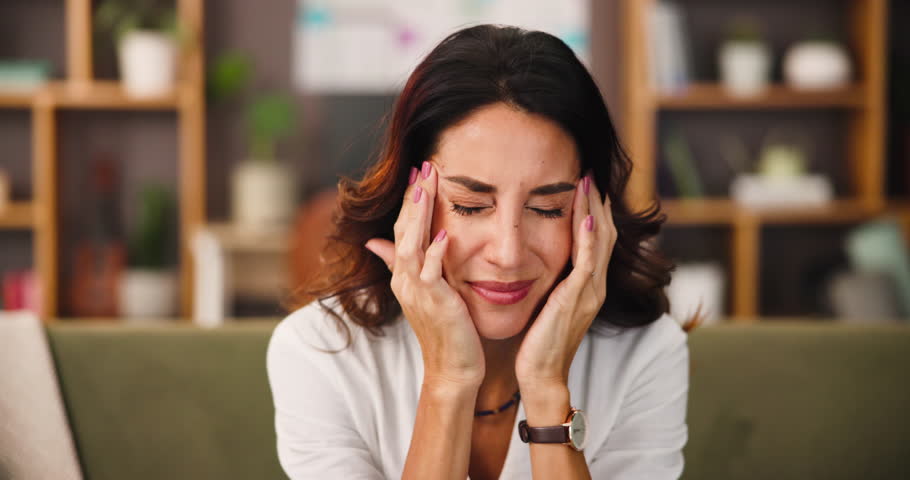 Headache, exhaustion and woman on sofa in home with brain fog, fatigue or hangover recovery. Stress, mental health and female person with temple massage for pain, tired or burnout in apartment.