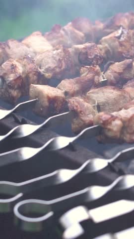 Grilling pork kebab on skewers at bbq, cooking process. Vertical footage