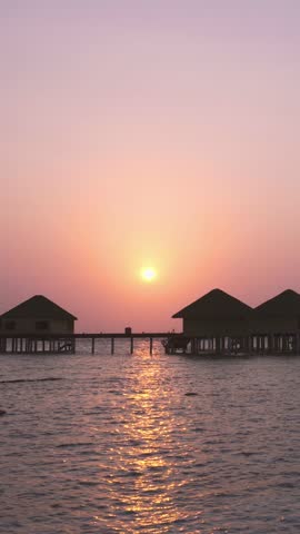 Sunset scene at Maldives beach, luxury water lodges. Travel destinations. Vertical footage