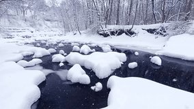 A  serene creek flows through a forest, with rocks and banks blanketed in deep snow during a heavy snowfall. - Powered by Shutterstock - Get 15% off with code: PIKWIZARD15