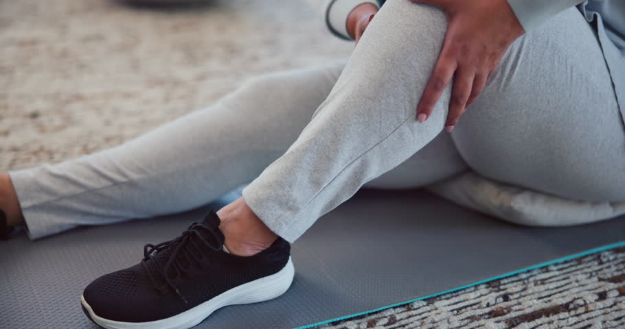 Injury, legs and person with cramp, massage and muscle tension from strain in gym, fitness or hurt. Wellness, hands and joint pain for senior athlete on floor, arthritis or recovery from inflammation