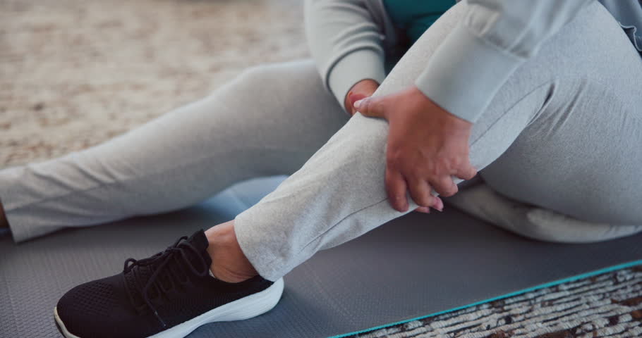 Injury, legs and person with cramp, massage and muscle tension from strain in gym, fitness or hurt. Wellness, hands and joint pain for senior athlete on floor, arthritis or recovery from inflammation