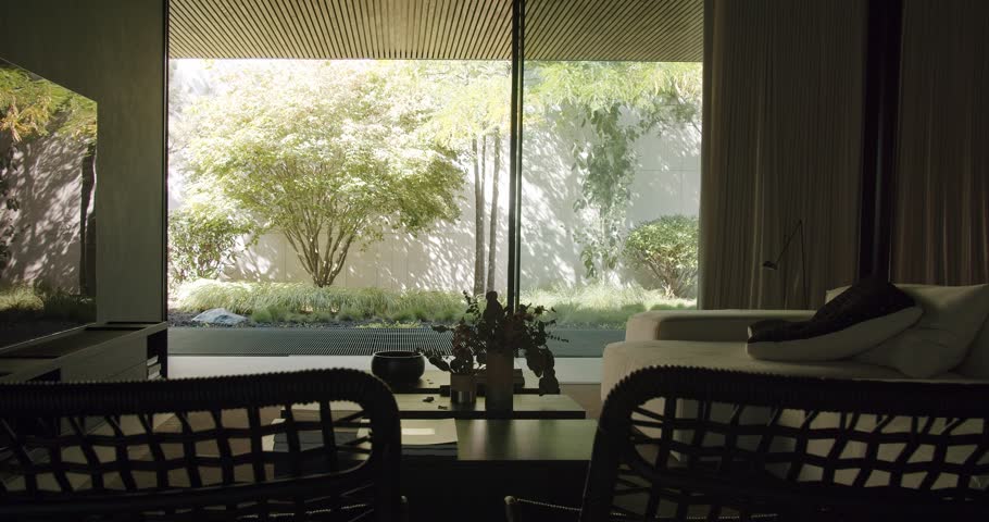 Contemporary living space with stylish decor and expansive view to a serene garden, illustrating modern indoor-outdoor living design. Elegant Modern Living Room Overlooking Tranquil Garden View