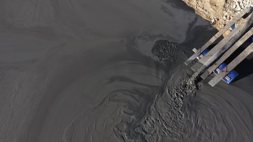 Aerial slow motion view of mining residuals flowing into decanting pond from a copper mine. Geamana, Rosia Montana Romania