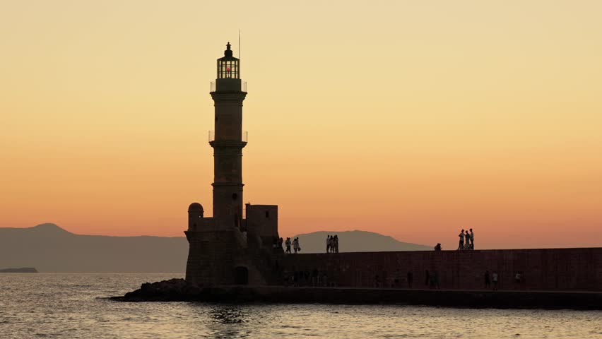Colorful sunset behind Venetian era lighthouse in Chania, Crete