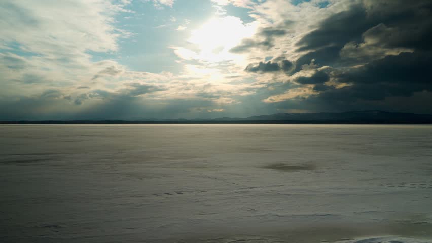Panoramic view of the frozen freshwater lake at sunset. Cloudy sky. Beautiful natural landscape.