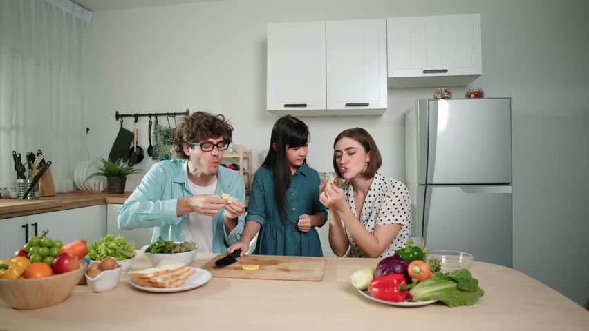 Happy caucasian father and mother sitting and eating fruit at modern kitchen. Energetic family spend time together by enjoy eating fruit or healthy fruit with kitchenware and fruit on table. Pedagogy.