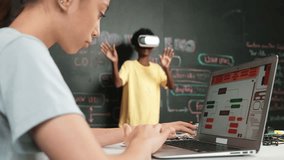 Closeup of school girl hand coding program while african student using VR interact with metaworld. Smart boy wearing virtual reality glasses and playing video games at innovative class. Edification - Powered by Shutterstock - Get 15% off with code: PIKWIZARD15