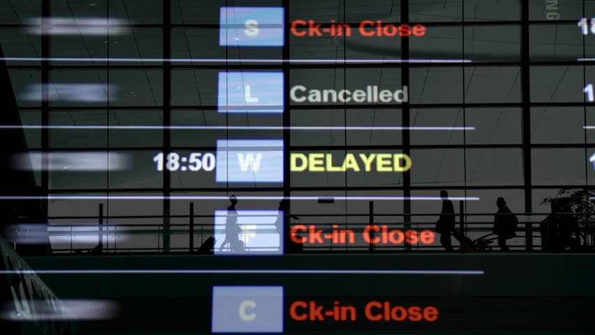 Flights delayed and canceled on departure board, flight delay footage. Device screen with airport flight information