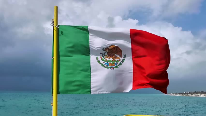Mexican green white red flag and emblem with blue sky and clouds on the ferry to Cozumel island in Playa del Carmen Quintana Roo Mexico.